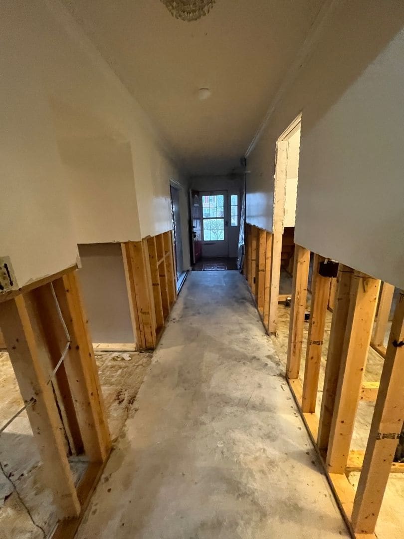 Hallway opened to the studs with wet drywall and flooring removed