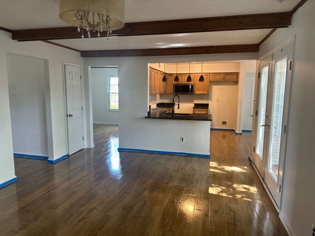 Rebuilt open-plan living room with new hardwood floors, fresh paint and the kitchen beyond