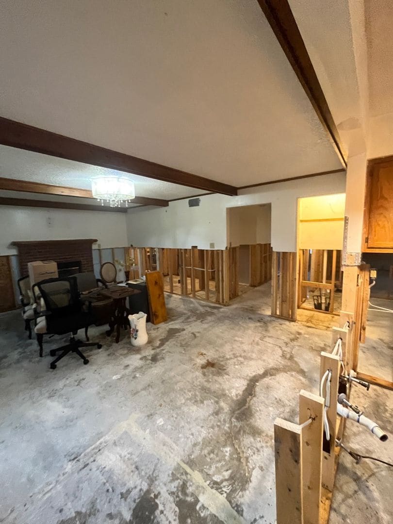 The same living room during the job, walls opened to the studs and the floor stripped to dry